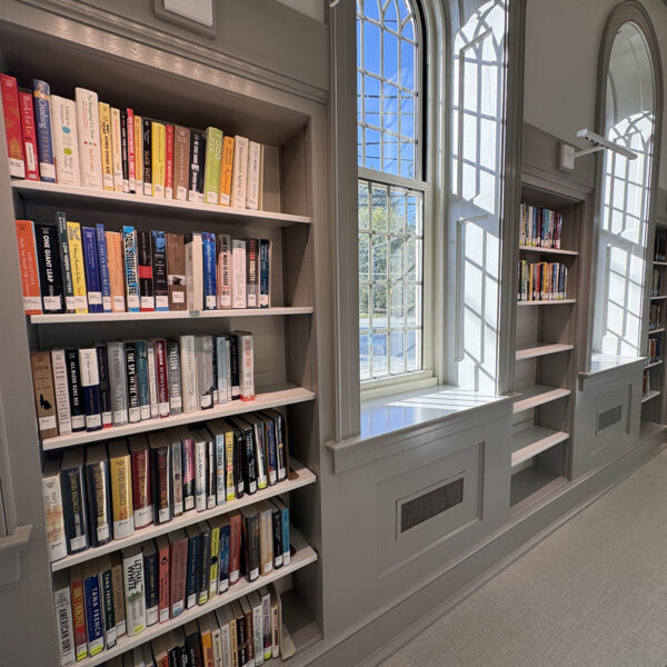 Cases of books along the walls in the main reading room, interspersed with arched windows.