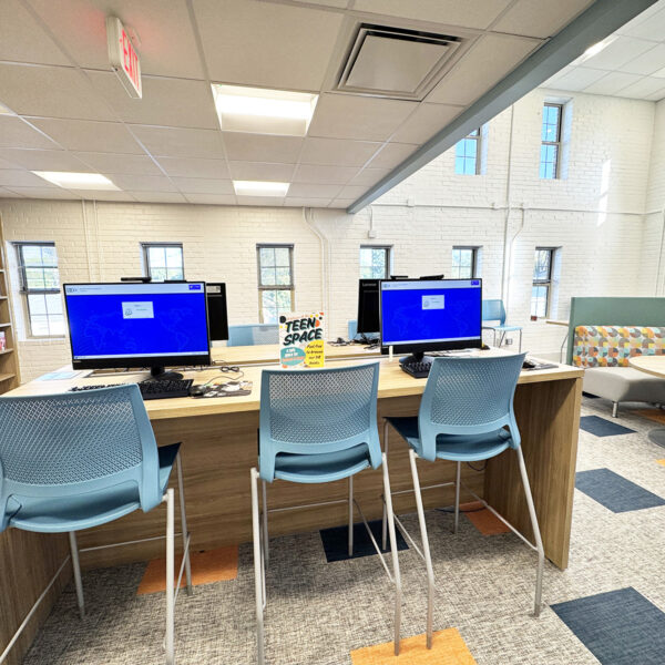 A table of computers with a sign saying Teen Space.