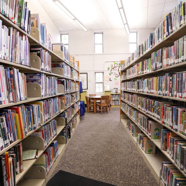 Row of bookshelves in the children's area, with a table and chairs at the end