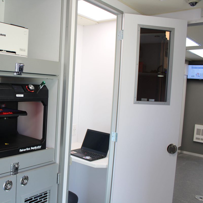 Small booth-like space with the door open and a laptop on the counter