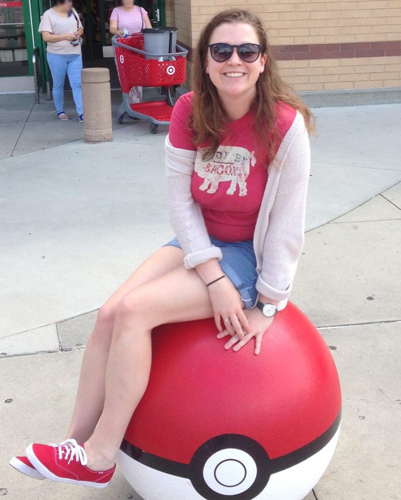Julia sitting balanced on top of life-sized Poke Ball