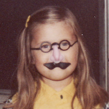 Laura as a child, wearing the classic glasses-nose-and-mustache costume