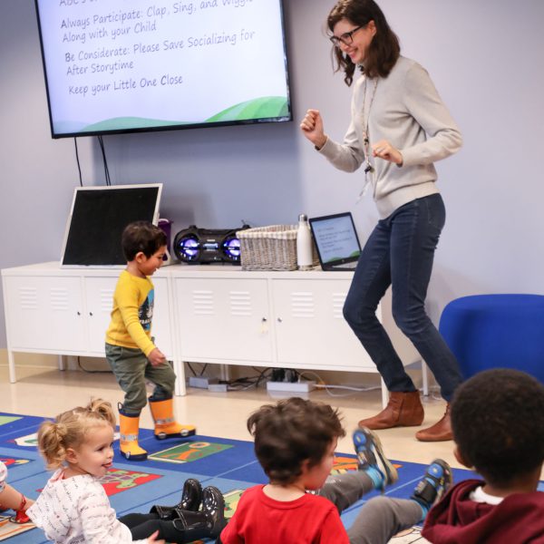 Librarian and small child dancing at the front of the room as other children watch