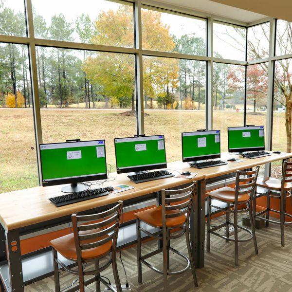 Computers in the teen area at East Regional Library, lined up in front of a large window looking out onto a natural area