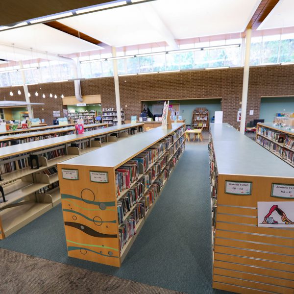 Tall open space with lots of low bookshelves. The closest ones have signs saying "Juvenile Fiction"