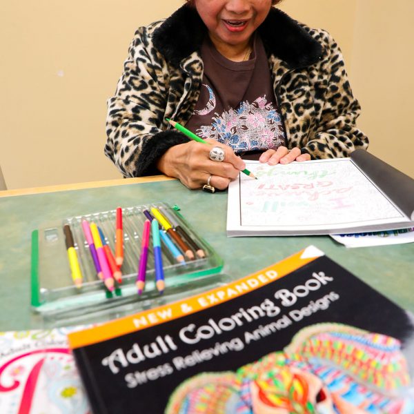 A woman uses colored pencils to work on an adult coloring book