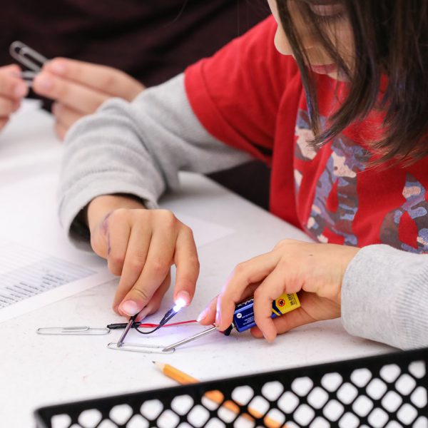 A teen connects a circuit to light up an LED