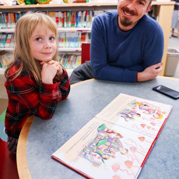 A man and child sit at a table with an open picture book