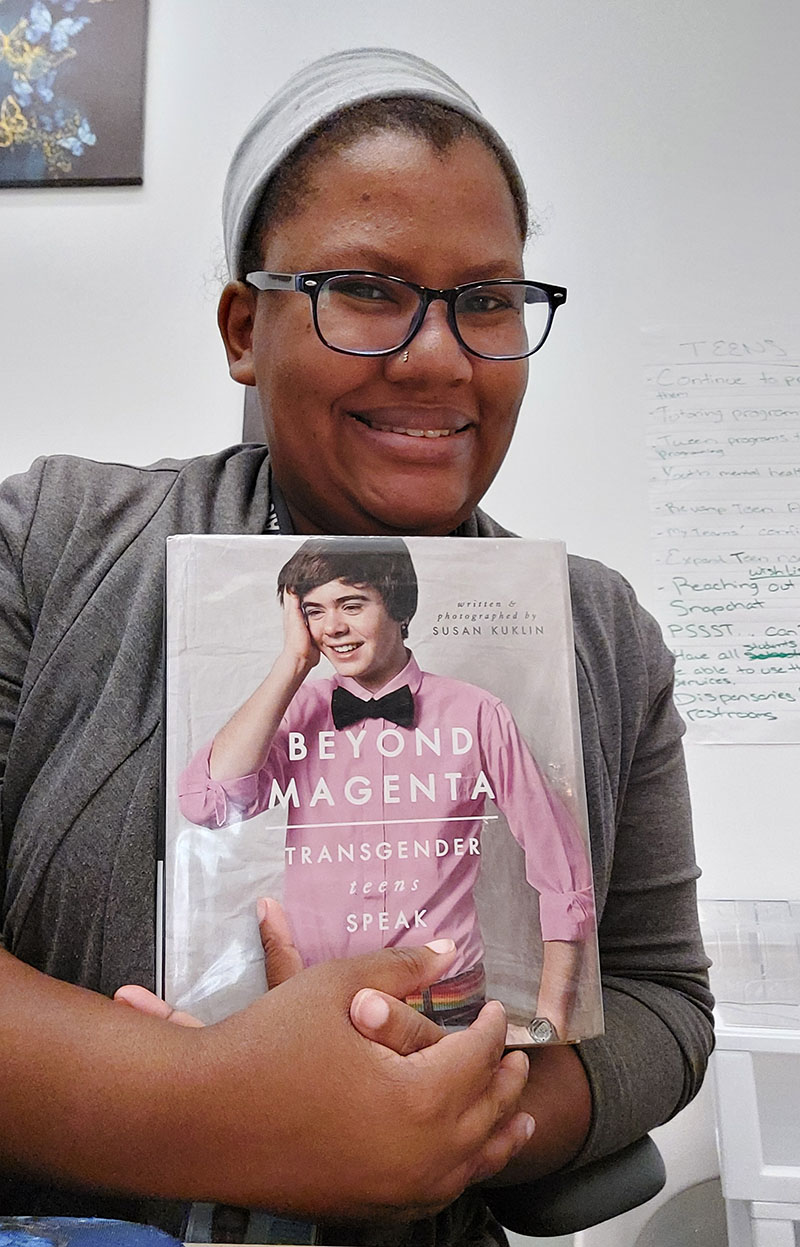 LaShaunda holding up the book "Beyond Magenta: Transgender Teens Speak."