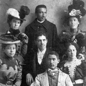 Formal group portrait of young Black men and women in dressy clothes. ca. 1900.