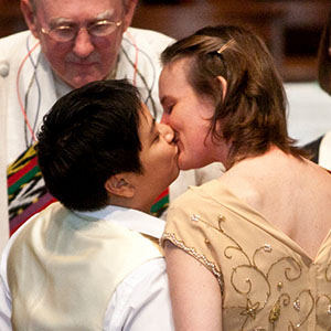 A queer couple kiss at their wedding