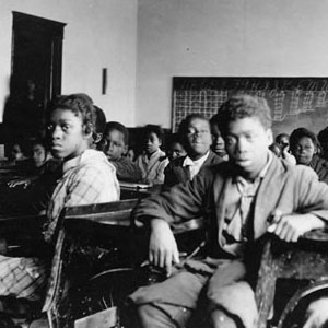 Black children seated at desks in a classroom with chalkboards lining the walls. Photo courtesy of Fisk University Franklin Library, Special Collections