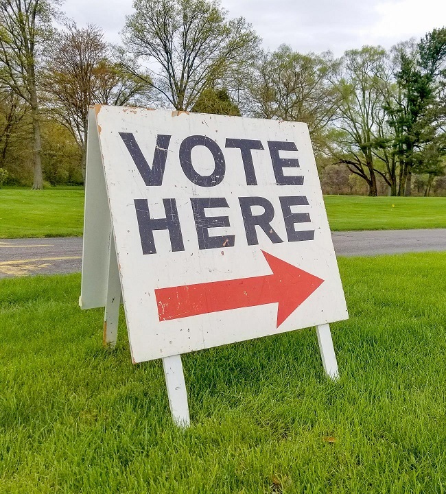 "Vote here" sign with an arrow pointing toward the polling place