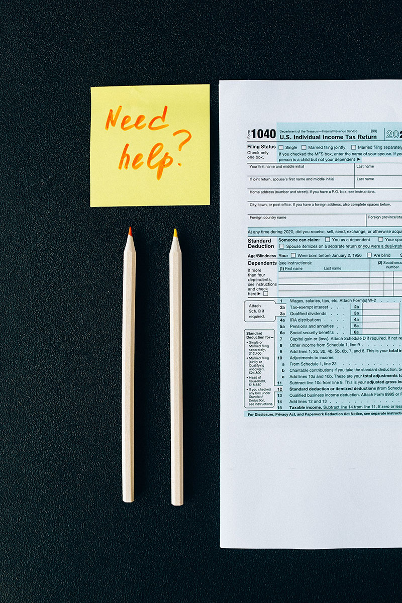 Post-it note reading "Need help?" next to a tax form 1040