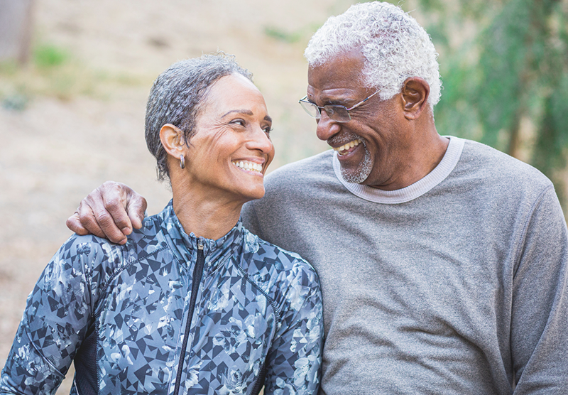 A grey-haired Black couple smile a each other lovingly.