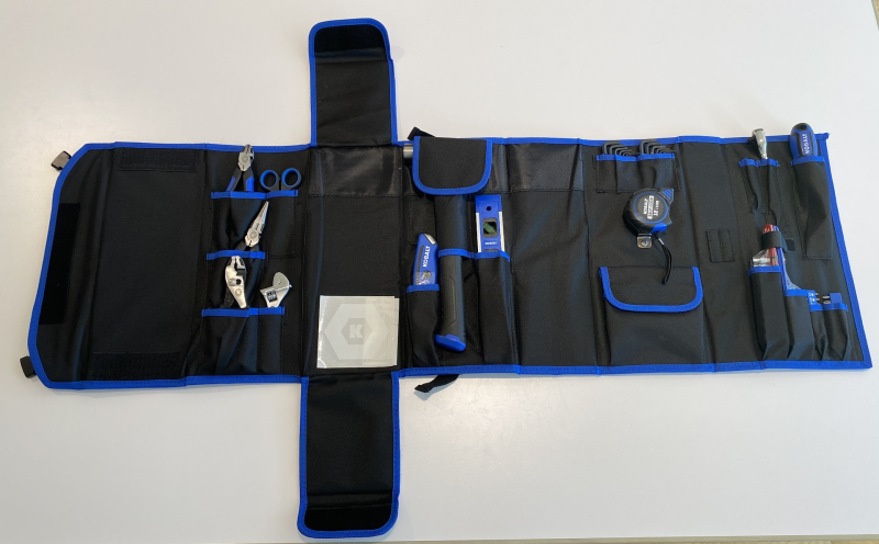 Unfolded kit showing tools including pliers, wrenches, scissors, a hammer, a tape measure, hex wrenches, a level, and more.