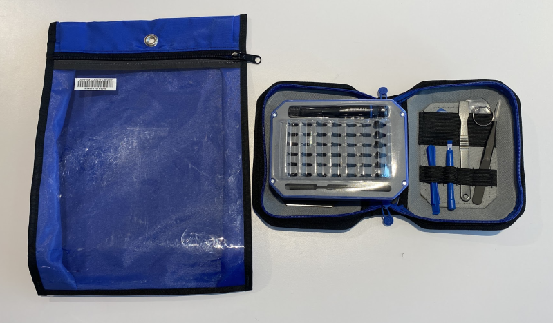 Opened kit containing an assortment of specialty bits with a handle, plus a few other tools such as tweezers and a paddle. The empty blue zippered bag sits next to the kit.