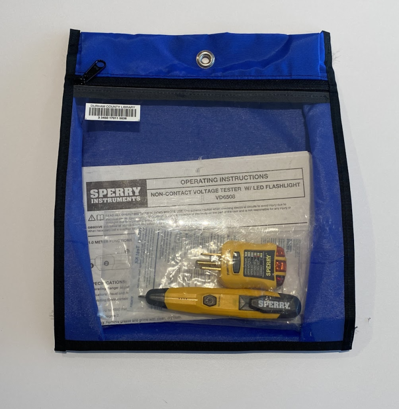 Blue zippered bag with a clear front, showing a yellow-and-black GFCI outlet tester and a yellow-and-black non-contact voltage tester