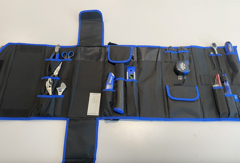 Unfolded kit showing tools including pliers, wrenches, scissors, a hammer, a tape measure, hex wrenches, a level, and more.