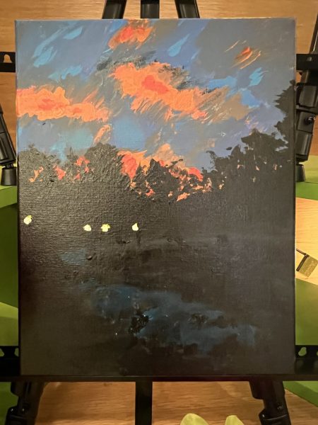 A dark landscape with glowing orange clouds in a dusky blue sky. A group of lights can be seen along what looks like a path that winds in front of the trees in the background - they may be torches, carried by shadowy figures.