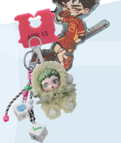 A keychain with various objects including a bread clip, a figure of a hockey player, a little figure with green hair and eyes wearing a furry outfit, and various dice and beads.