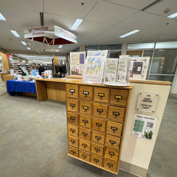 An old-fashioned wooden card catalog with information about checking out the seeds stored in its drawers.